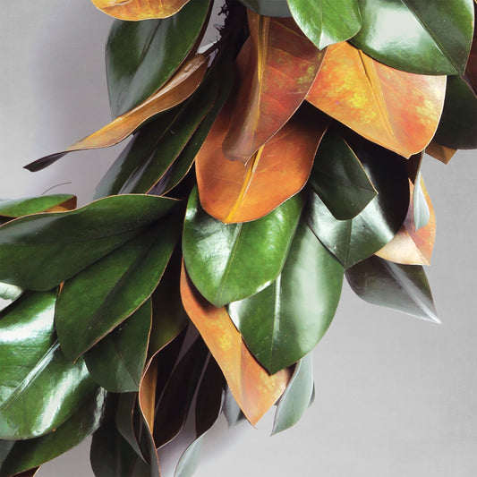 30" faux magnolia leaf wreath, closeup view of leaves, with gray background.