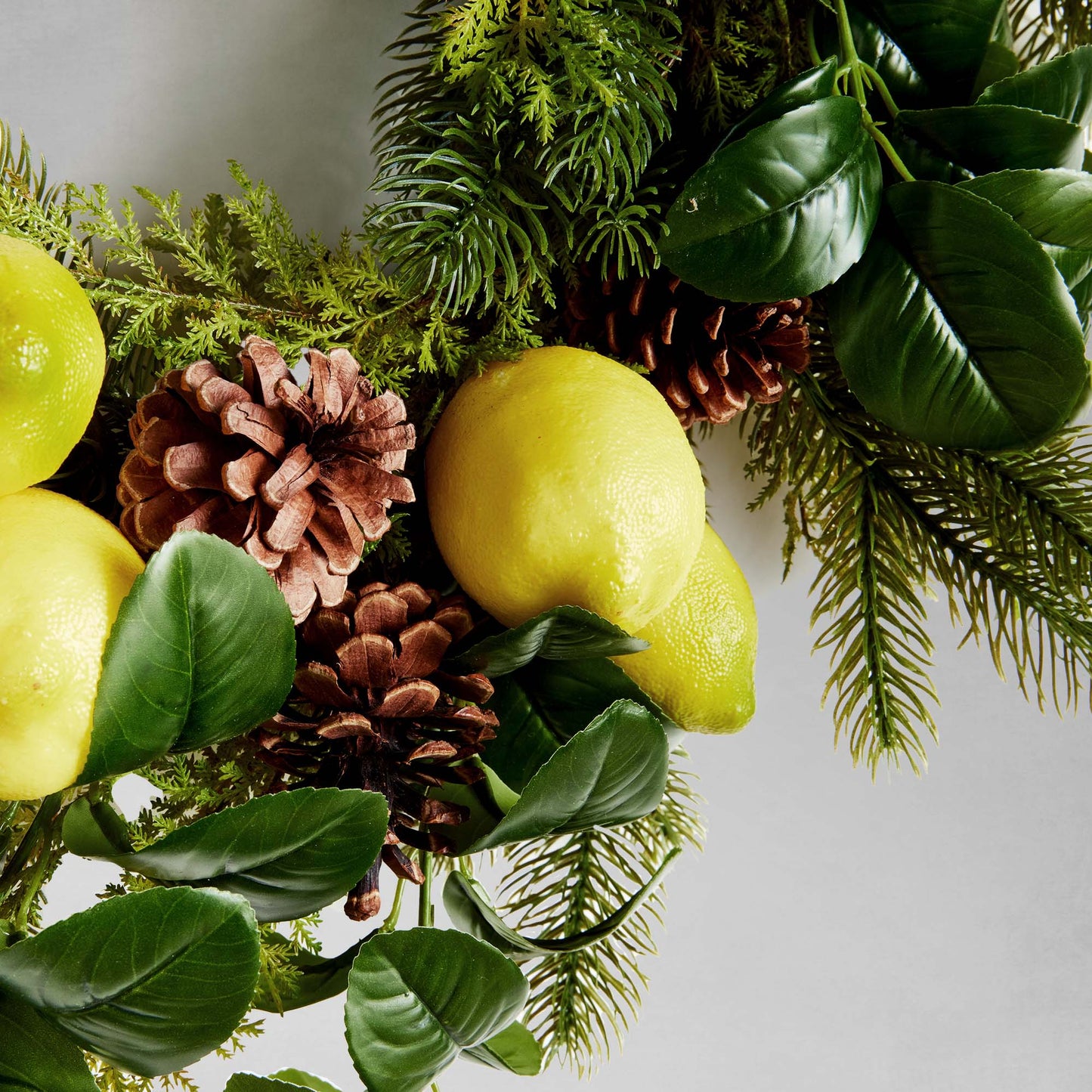 26" faux lemon and mixed botanicals wreath, closeup view, with gray background.