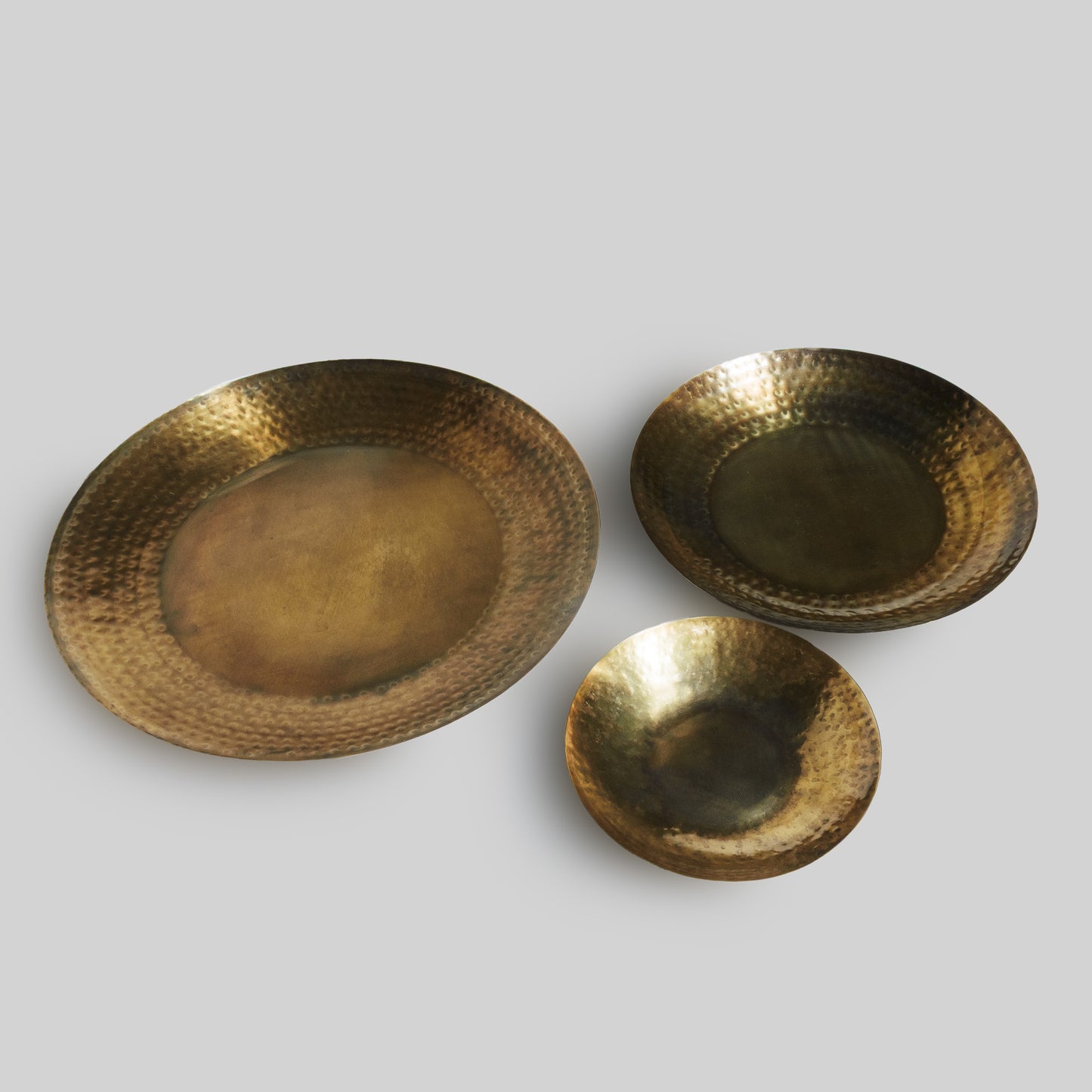 Set of three antique brass decorative trays with gray background.
