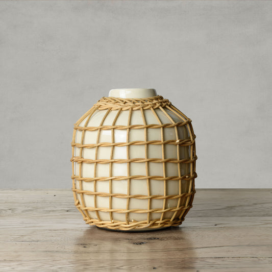 Artisanal natural rattan decorative ceramic vase on wood surface with gray background.