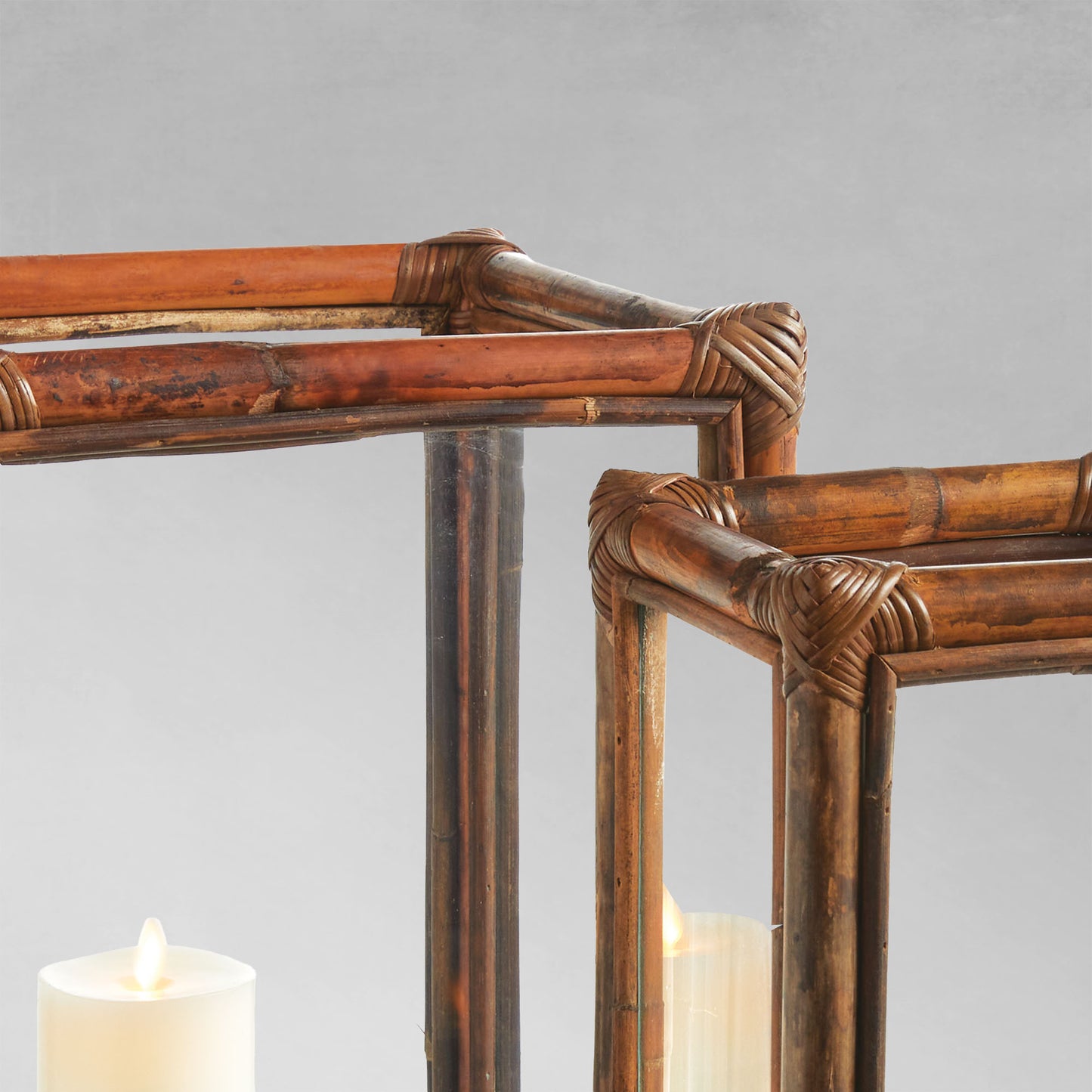 Cane rattan hurricane candleholders closeup view with gray background.