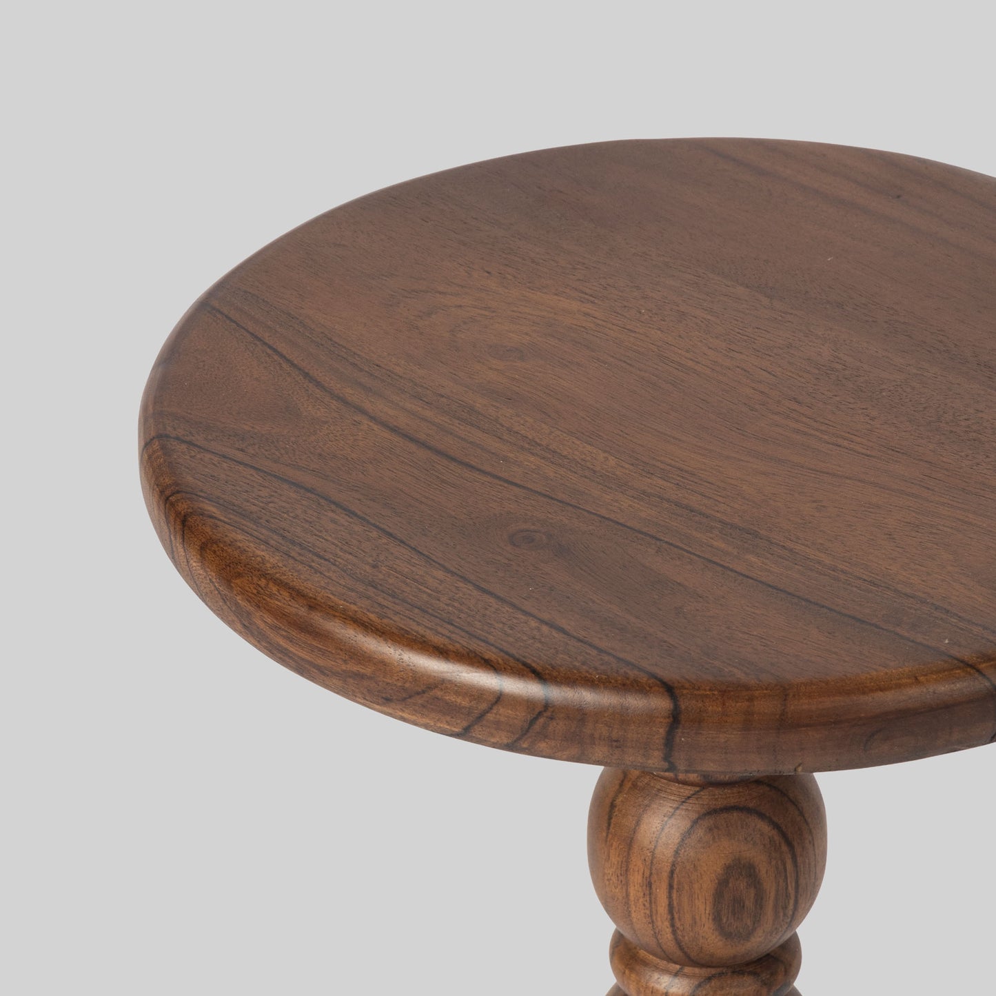 Round wooden side table with spindle design on a light gray background.