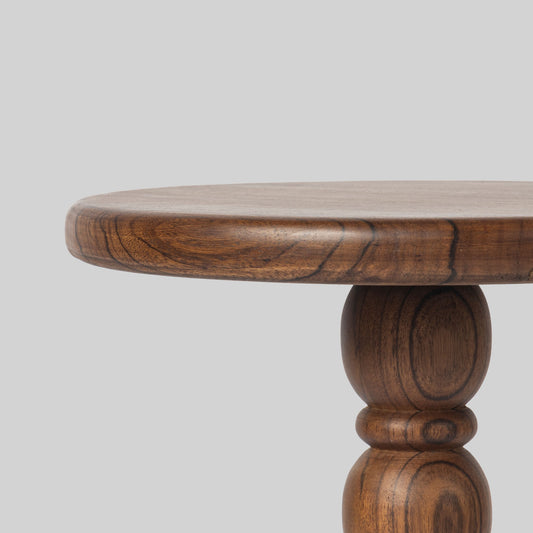 Round wooden side table with spindle design on a light gray background.