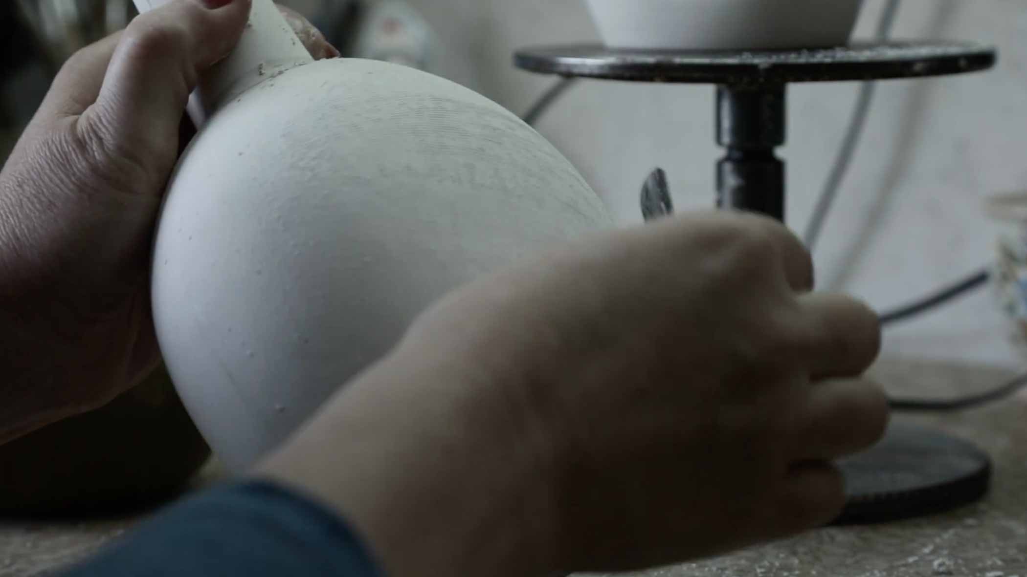 Chinese woman in Jingdezhen scraping ceramic pottery.