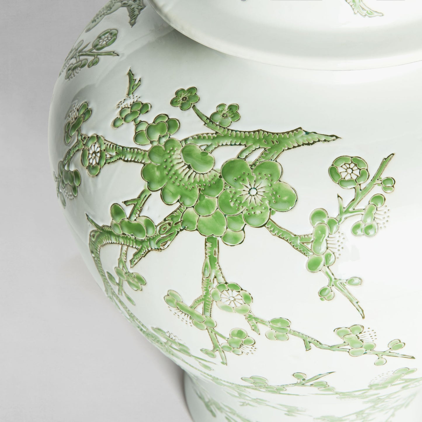Chinoiserie green and white porcelain ginger jar, closeup view of design with gray background.