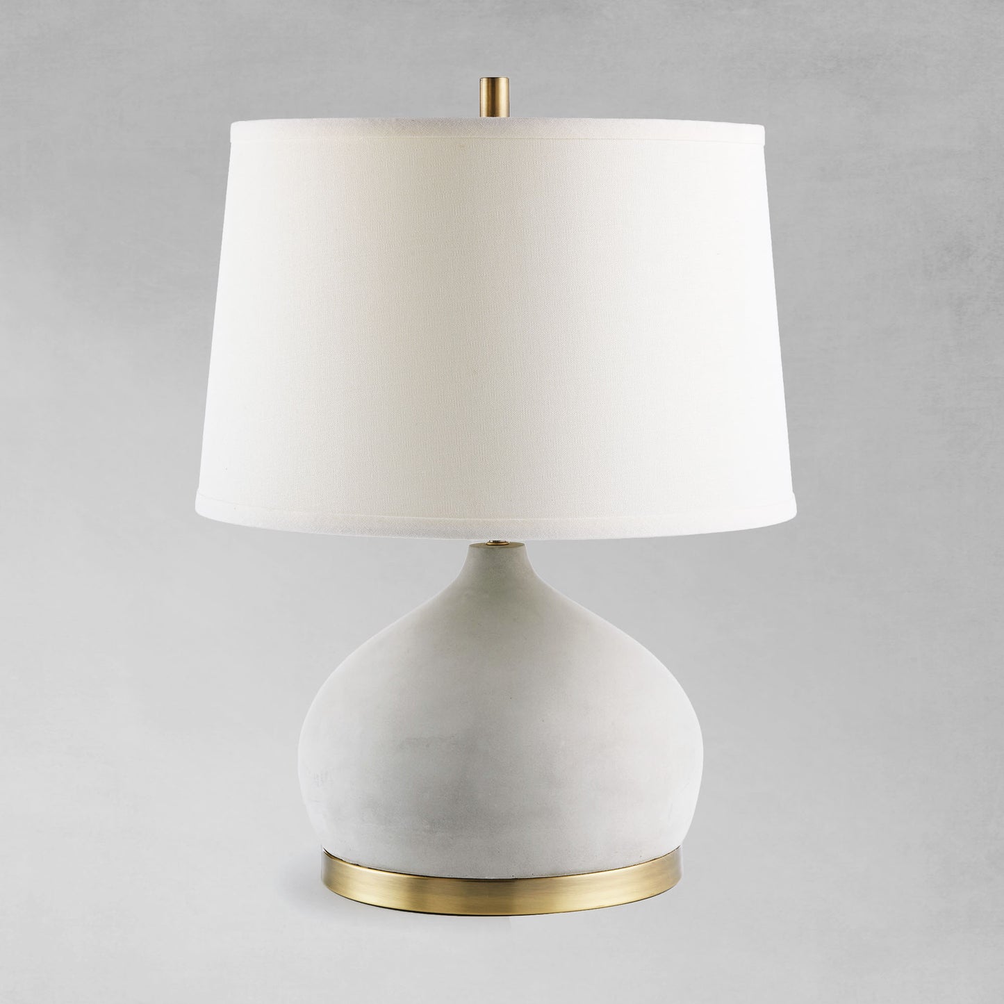 Contemporary concrete and antique brass table lamp with gray background.
