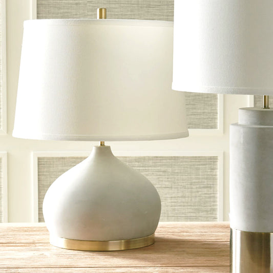 Contemporary concrete and antique brass table lamp on table.