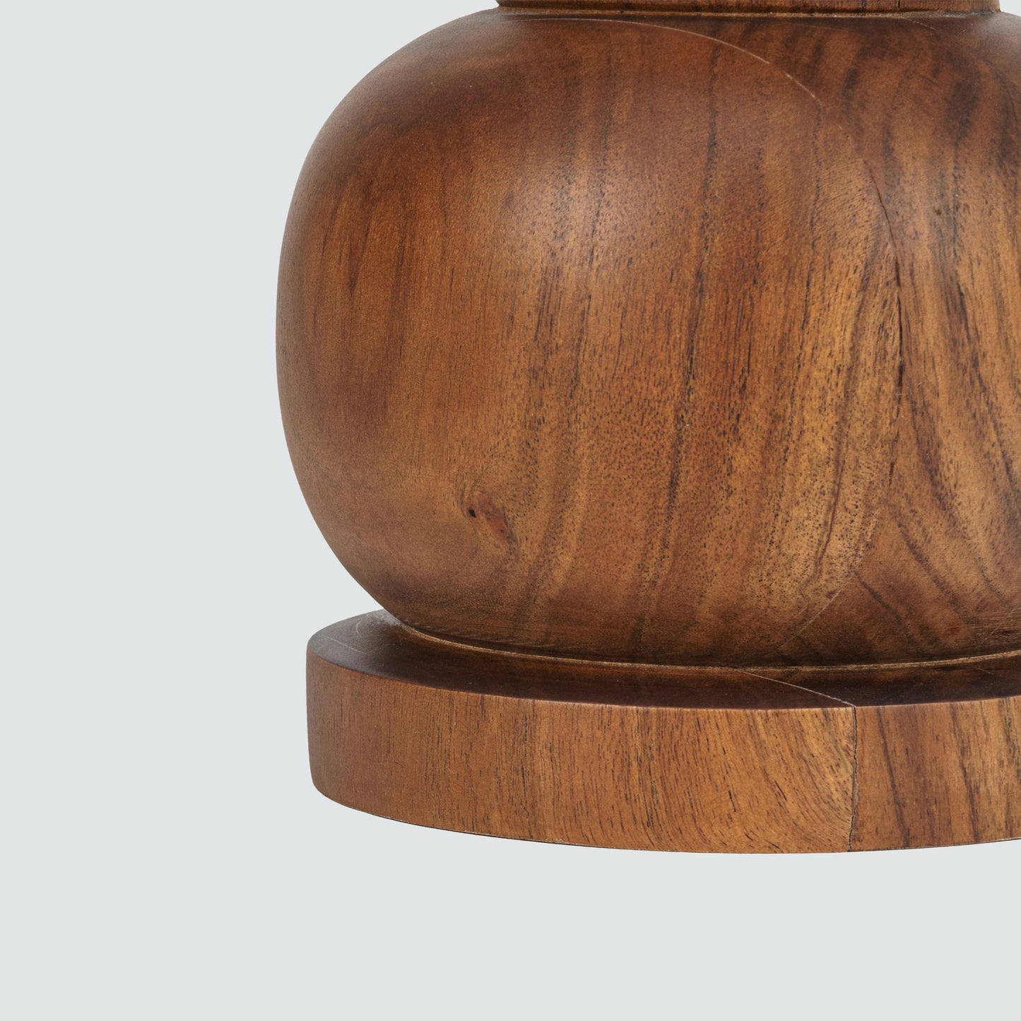 Closeup of base of wooden side table with a white marble top on a gray background.