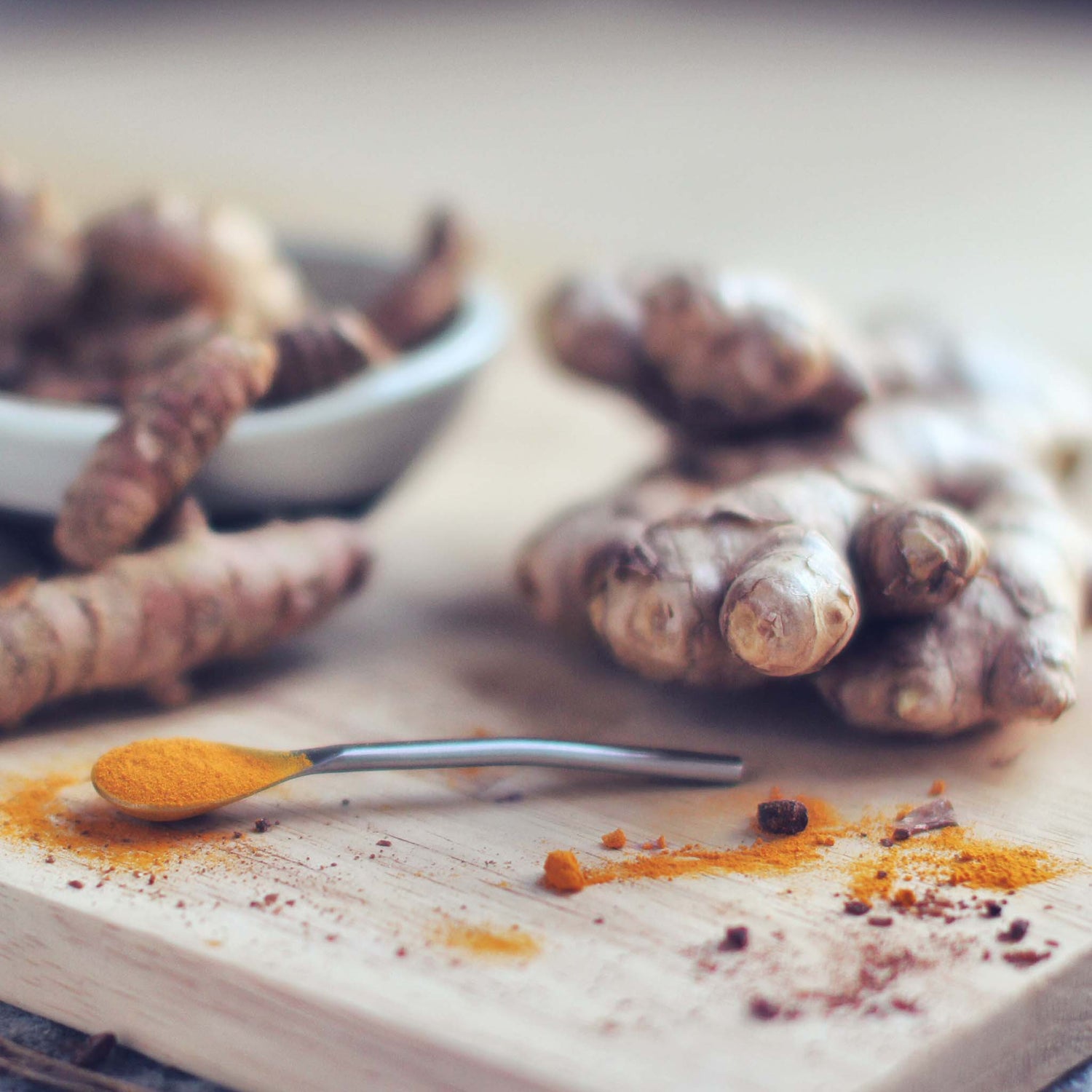 Cut ginger and ginger powder in spoon on cutting board.