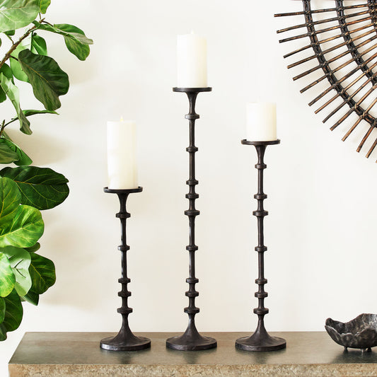 Dark bronze aluminum pillar candleholders stylized on console table with fiddle leaf fig.