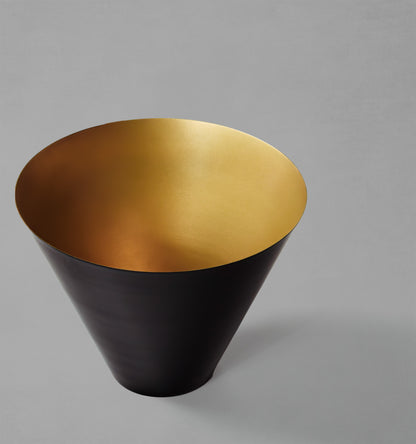 Large decorative black and gold bowl with gray background.