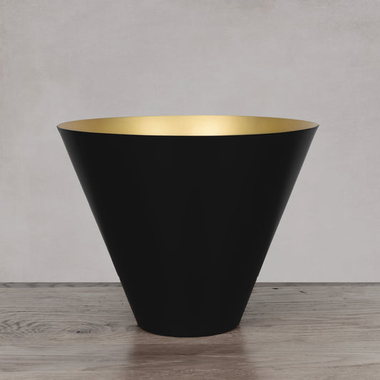 Decorative black and gold large bowl on light gray wood floor with light gray background.
