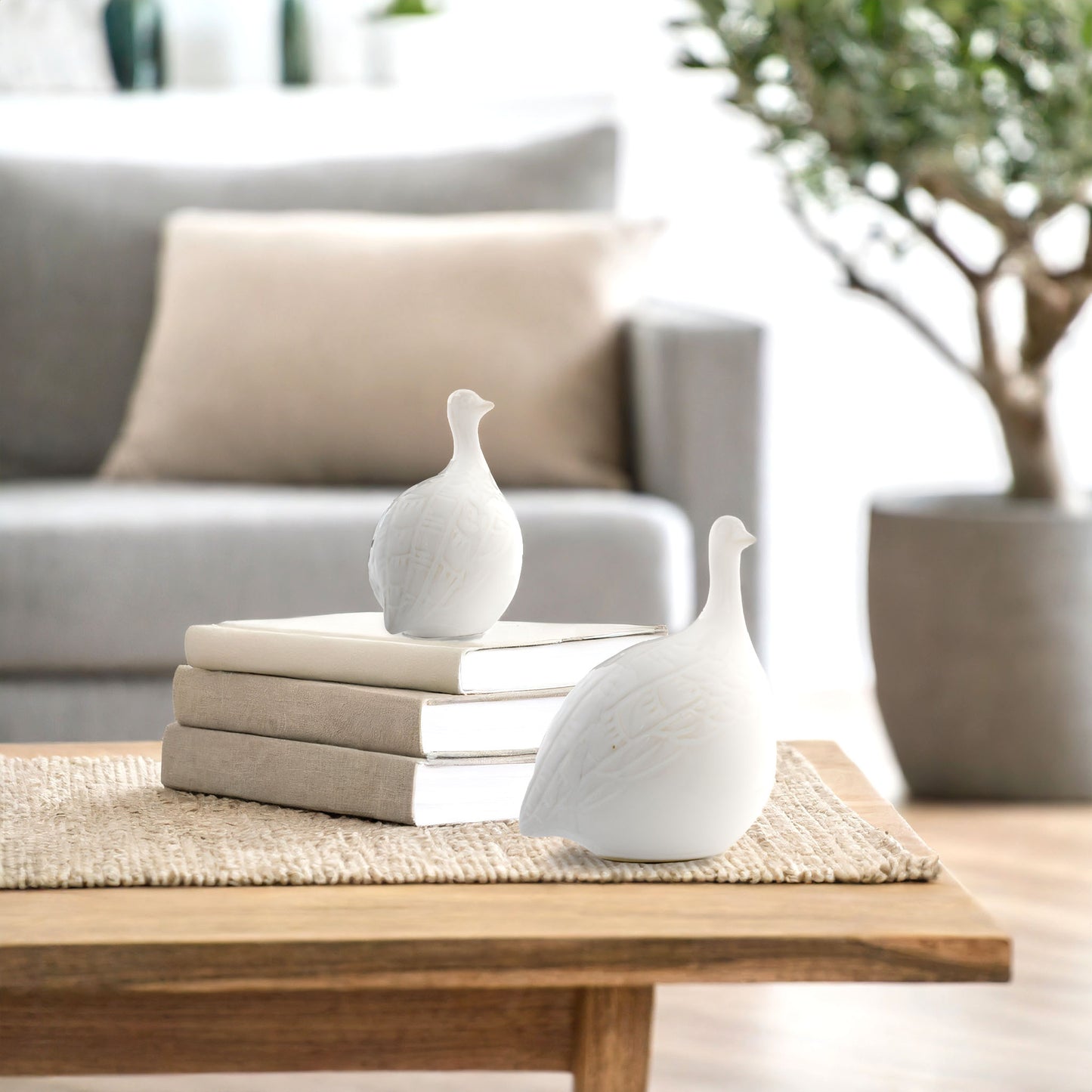 Decorative ceramic birds on coffee table stylized with books, in living room.
