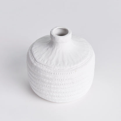 Top view of a decorative white ceramic textured vase on white background.