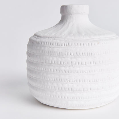 Closeup view of a decorative white ceramic textured vase with white background.