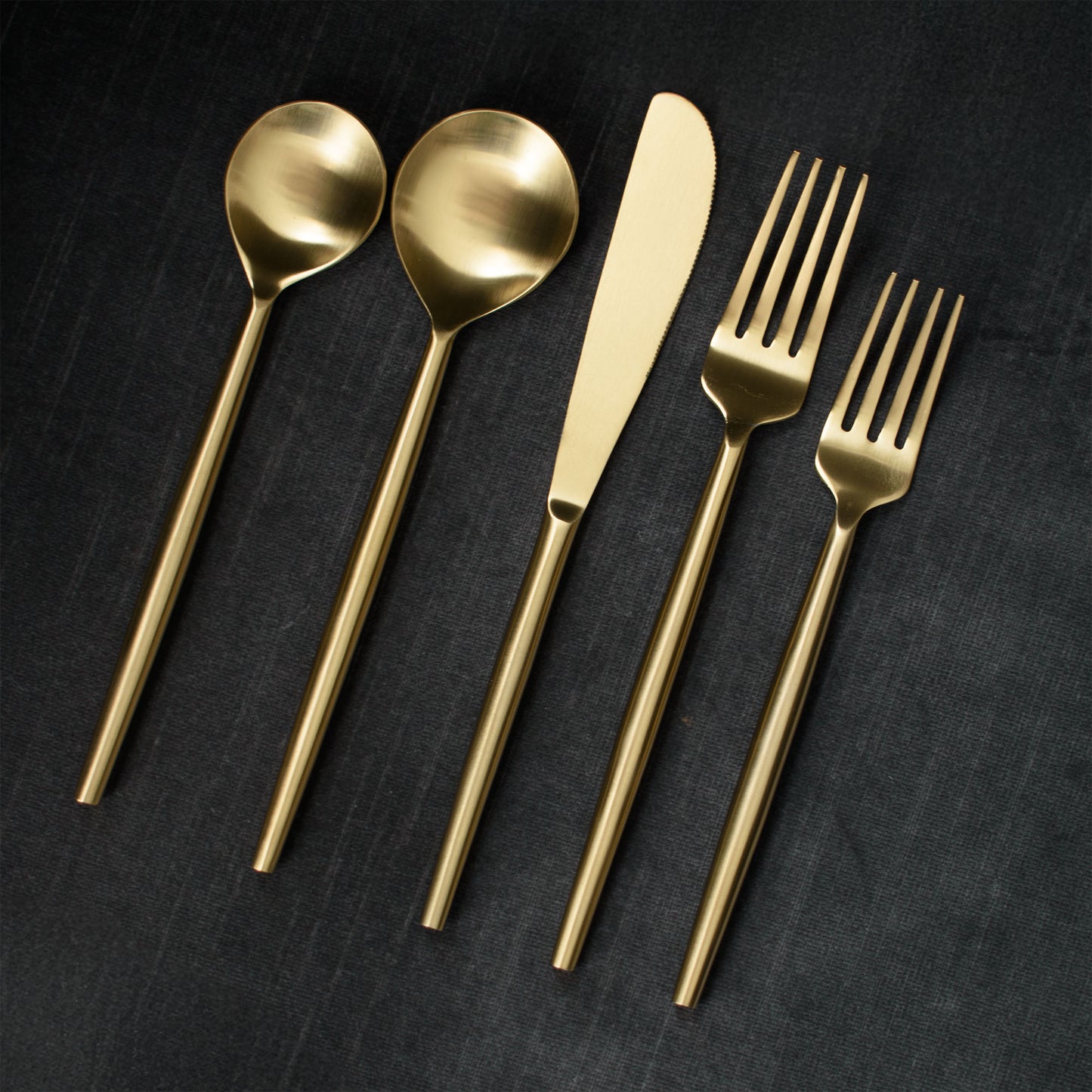 Matte gold flatware set on gray background.