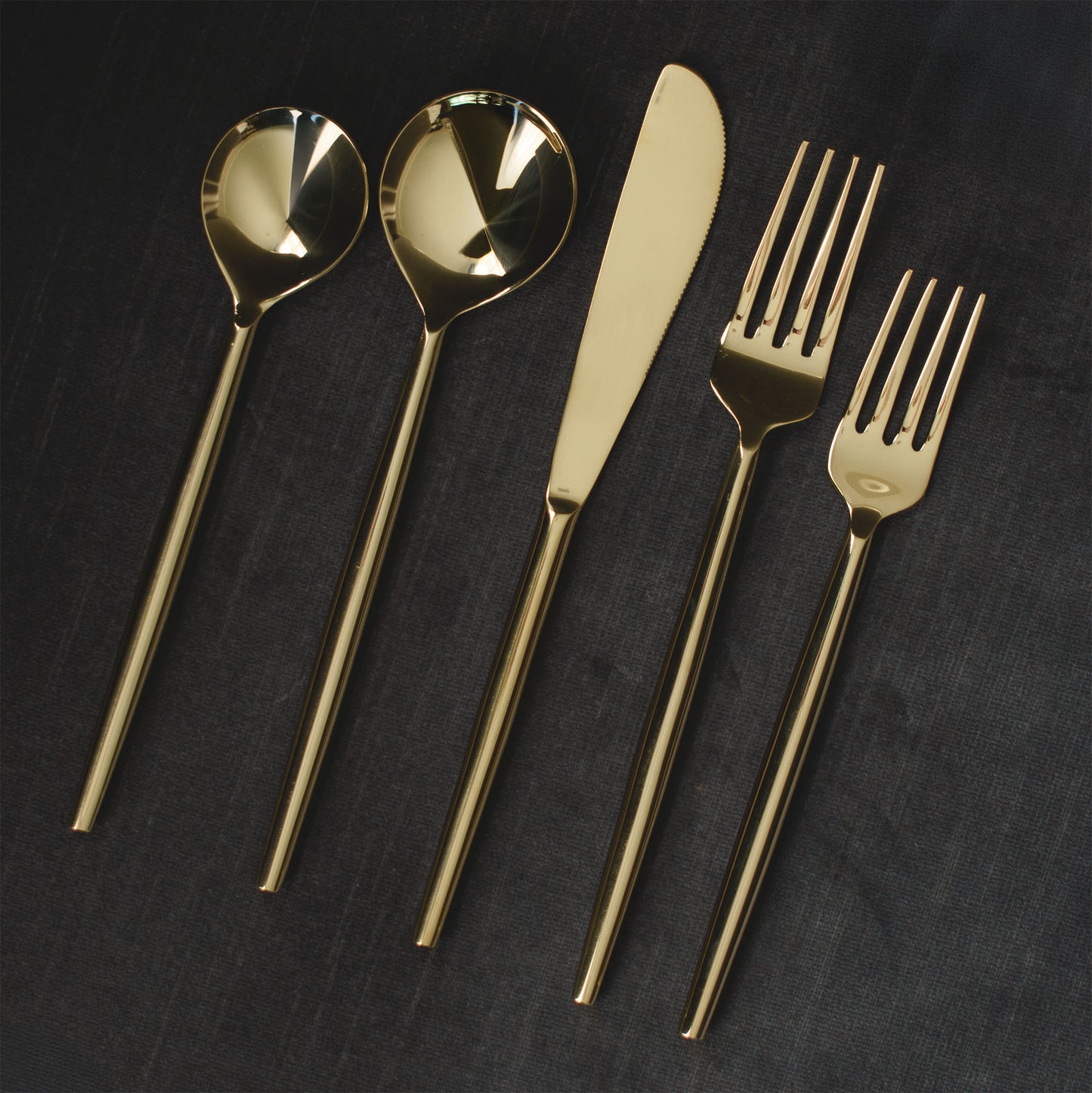 Polished gold flatware set with gray background.