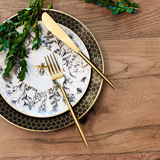 Gold polished flatware stylized on dining table with boxwood stems.