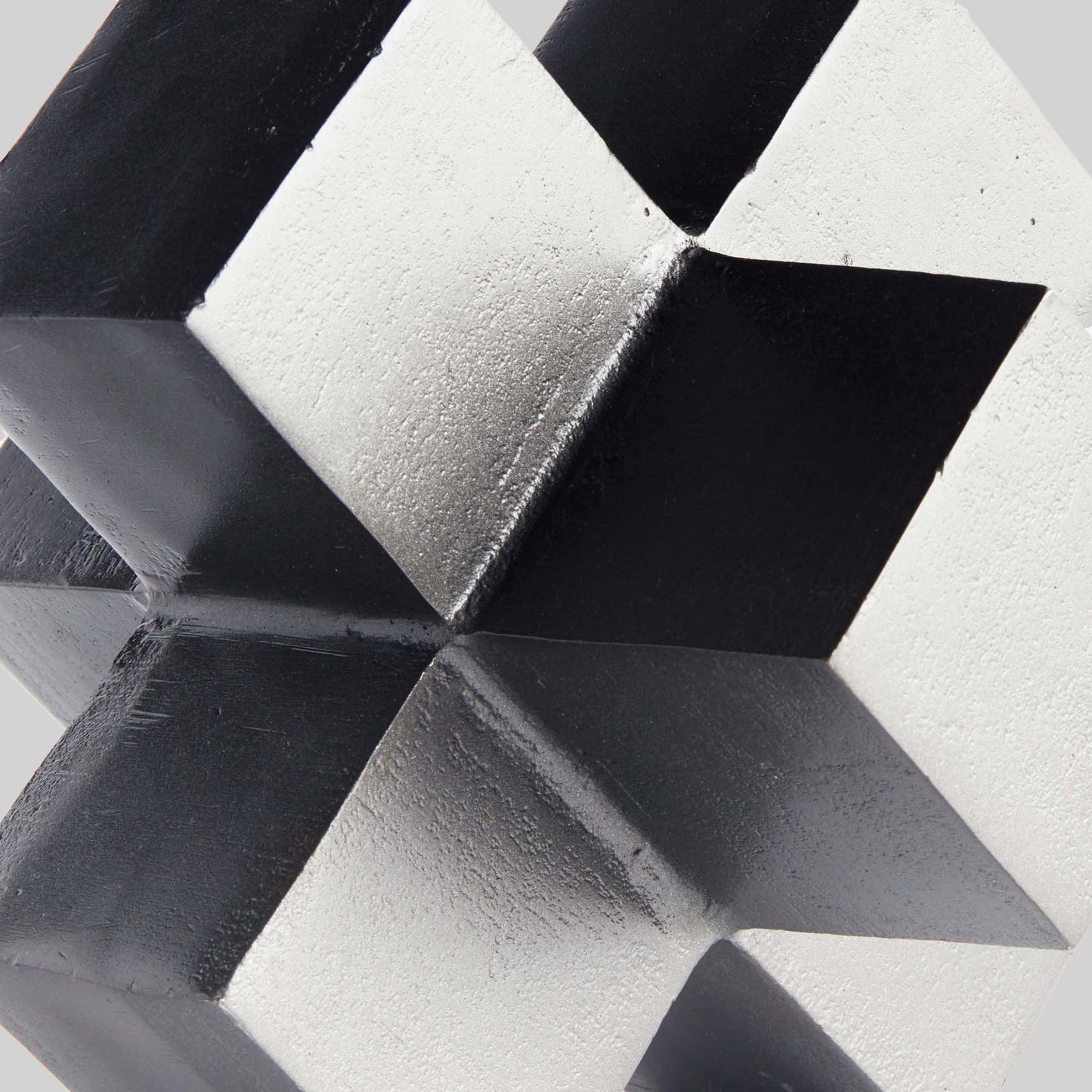 Closeup view of silver geometric plus sign decorative object with gray background.