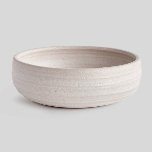 Hand-thrown white ceramic decorative bowl with gray background.