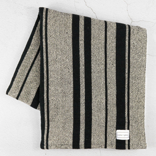 Handwoven striped cotton throw blanket on limestone surface.