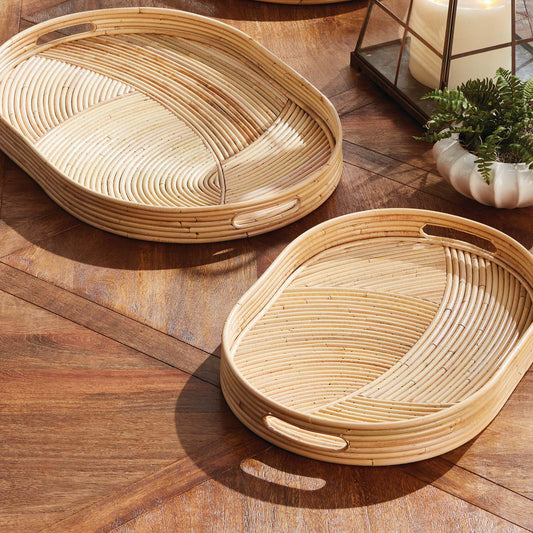 Handwoven oval rattan serving trays stylized on outdoor dining table.