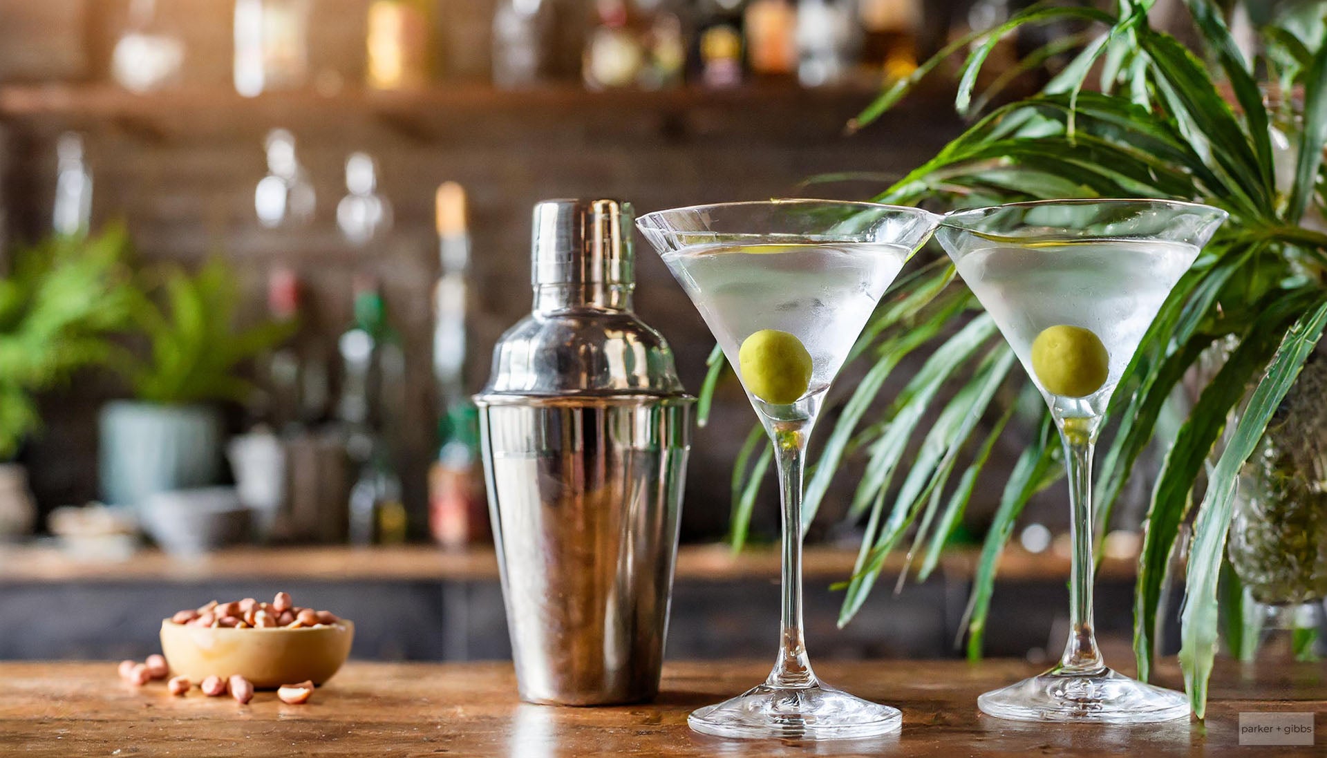 Home bar with martini glasses, martini shaker, and plants.