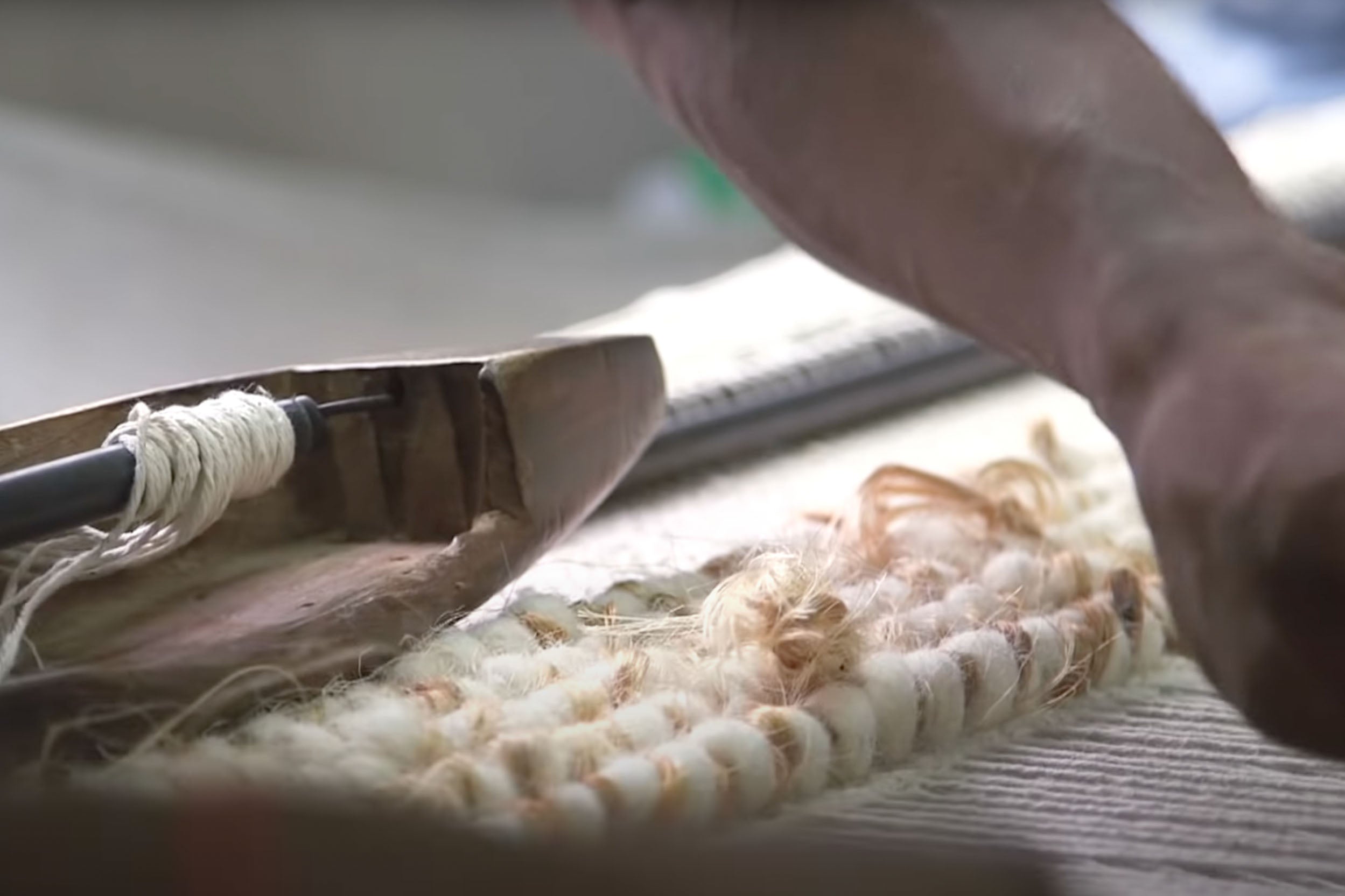 Indian man making a throw on a handloom.