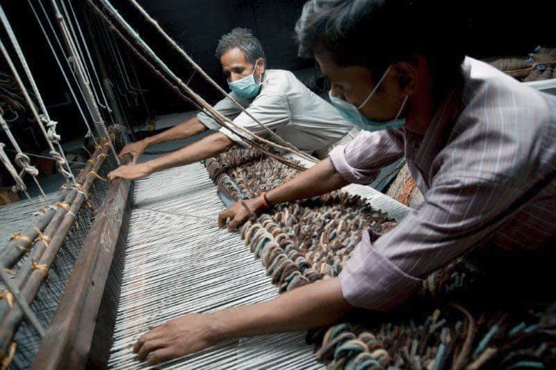 Two men in India using a handloom to make textiles.