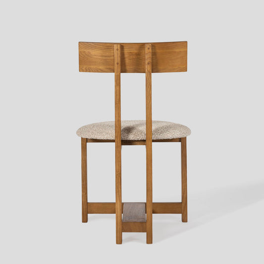 Wooden bar stool with a cushioned seat on a light gray background