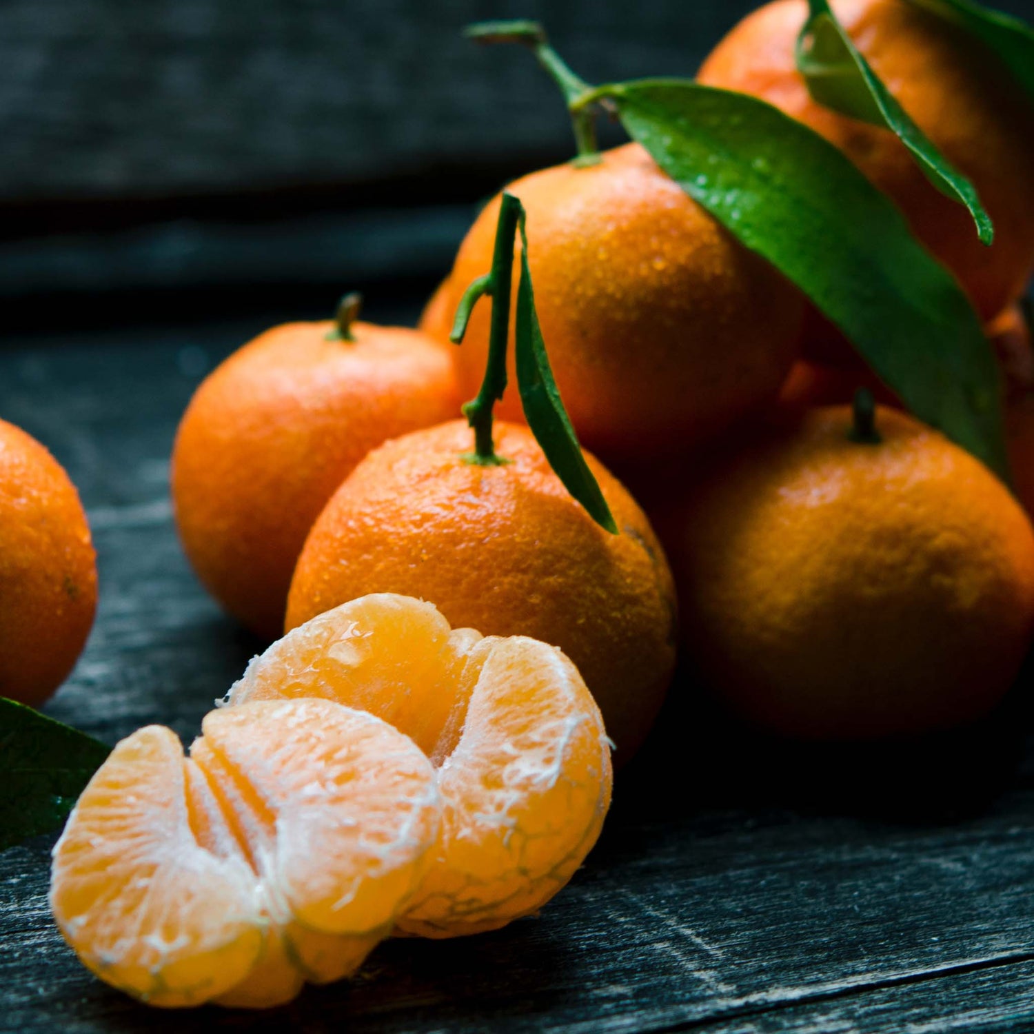 Japanese Satsuma mandarins on black wooden table.