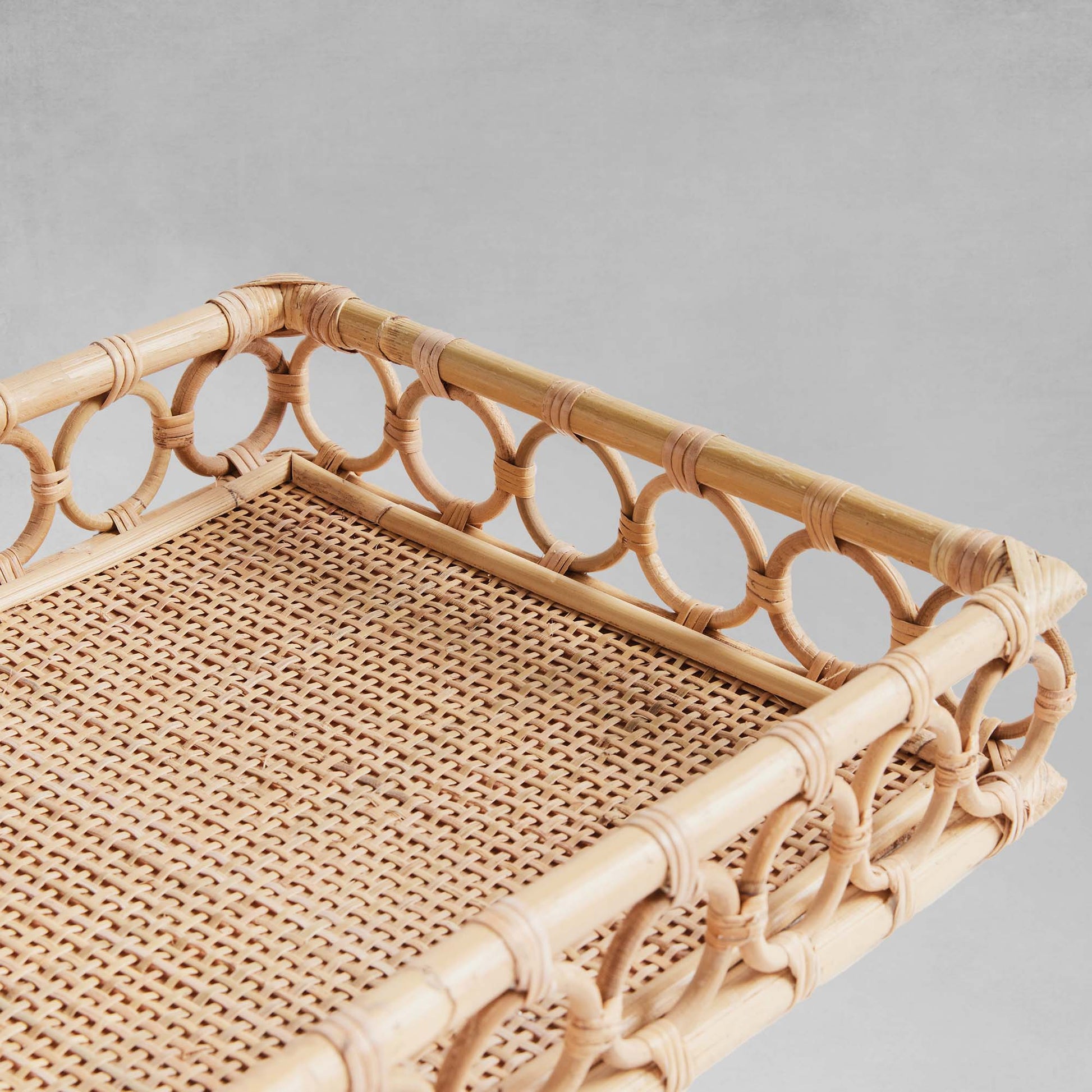 Lattice rectangular rattan serving trays closeup view with gray background.