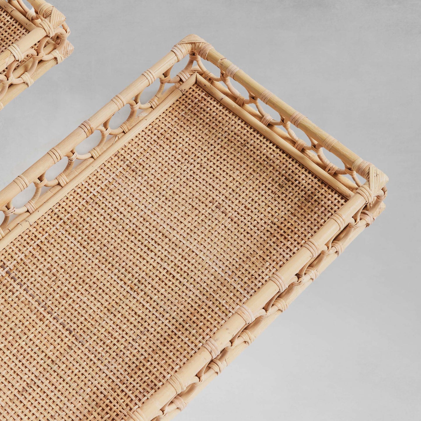 Lattice rectangular rattan serving trays closeup top view with gray background.
