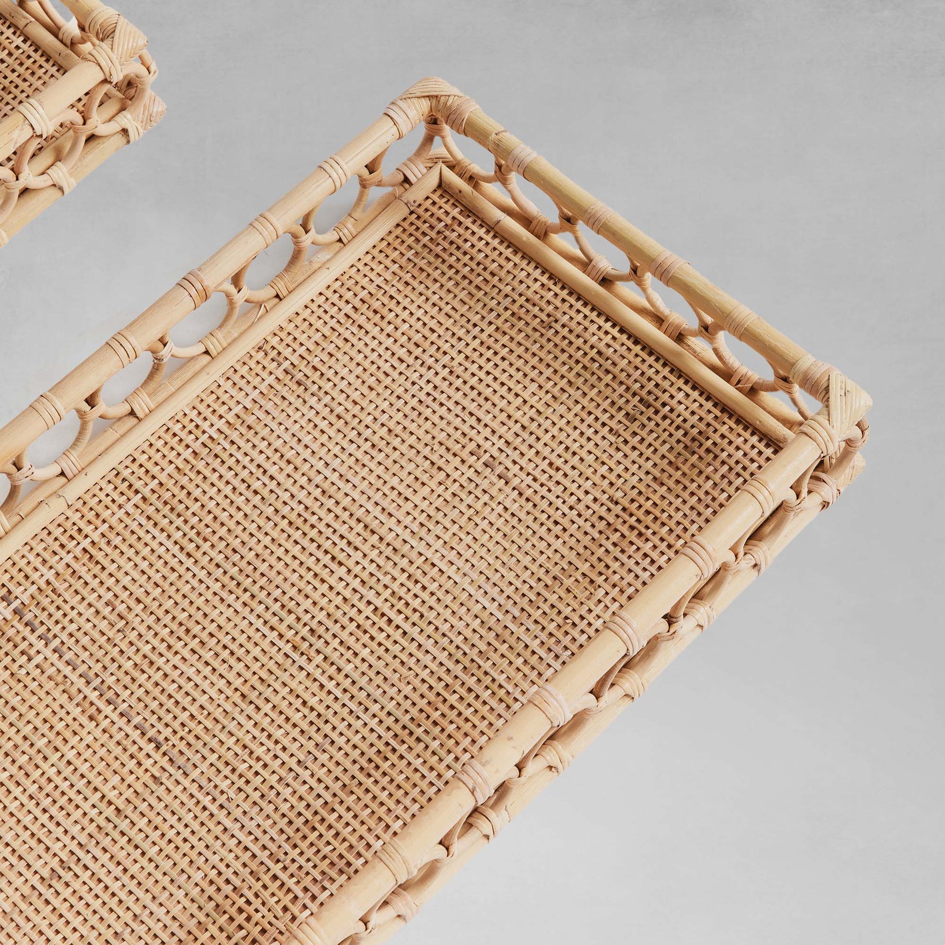 Lattice rectangular rattan serving trays closeup top view with gray background.