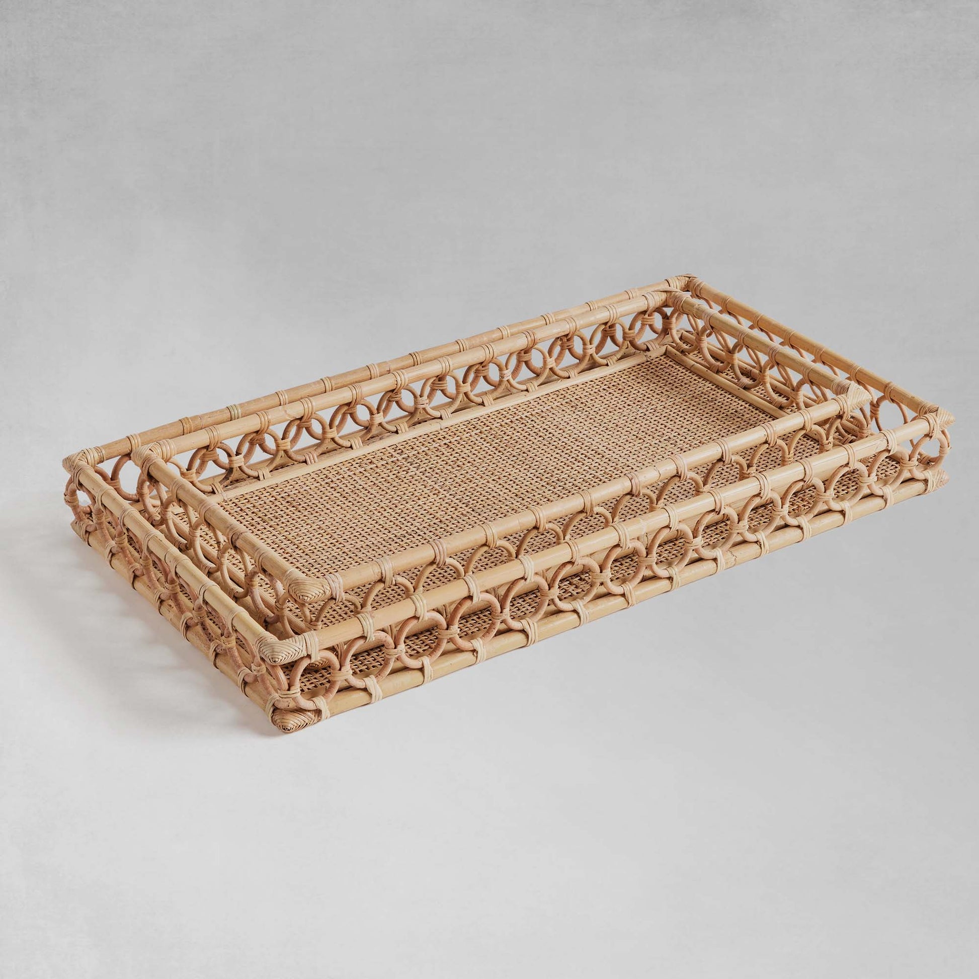 Lattice rectangular rattan serving trays stacked up with gray background.