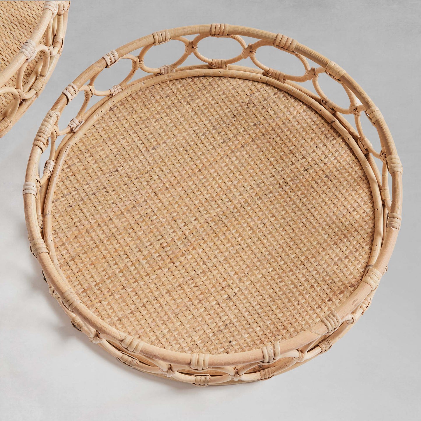 Lattice round rattan serving trays, top view, with gray background.