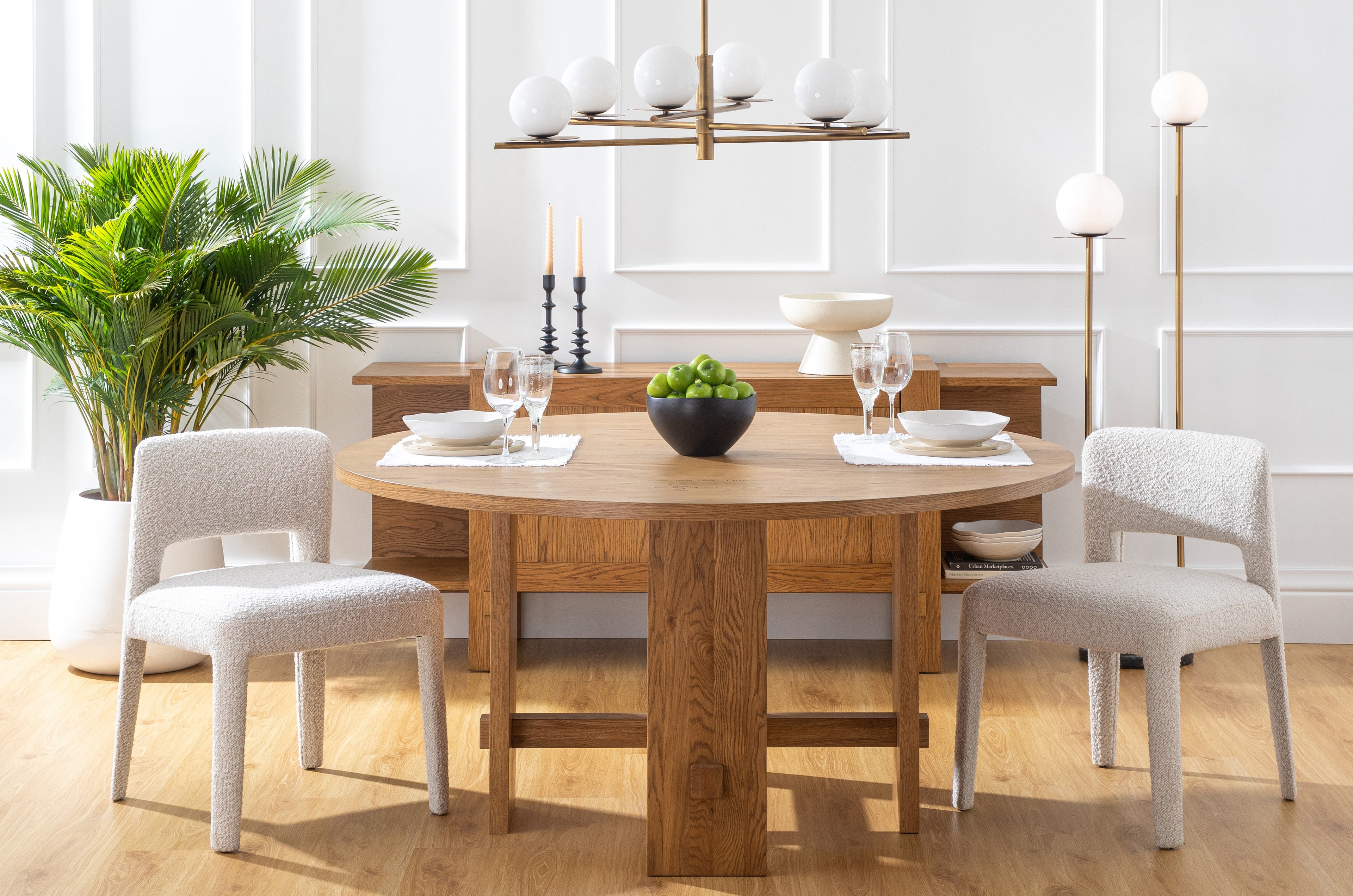 Stylish dining room table and chairs, console table, contemporary brass chandelier, and palm tree.