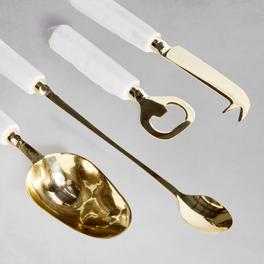 Marble and gold stainless steel barware tools set angled with gray background.