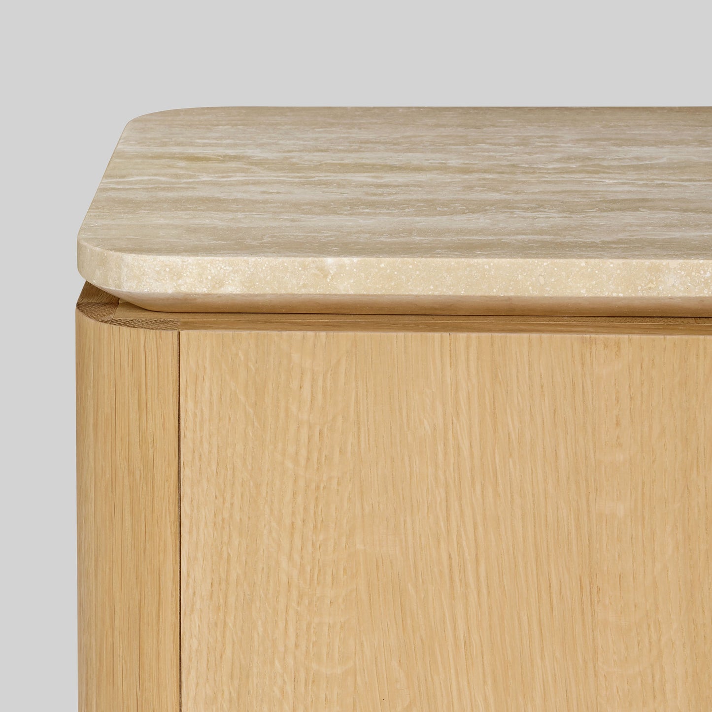 Wooden side table with a light oak finish and travertine top on a gray background.