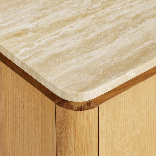 Wooden side table with a light oak finish and travertine top on a gray background.