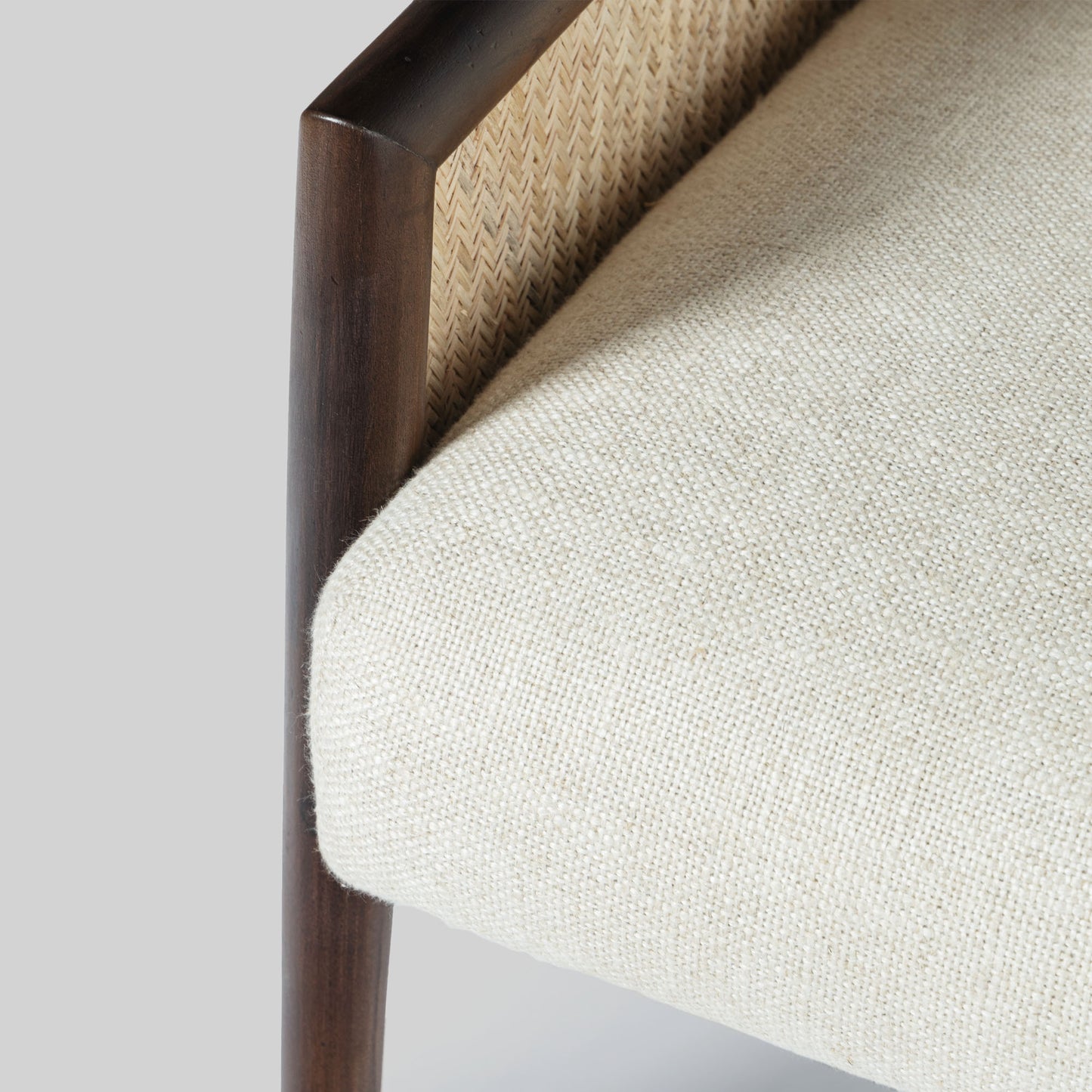Beige armchair with cane arms and wooden frame on a light gray background.
