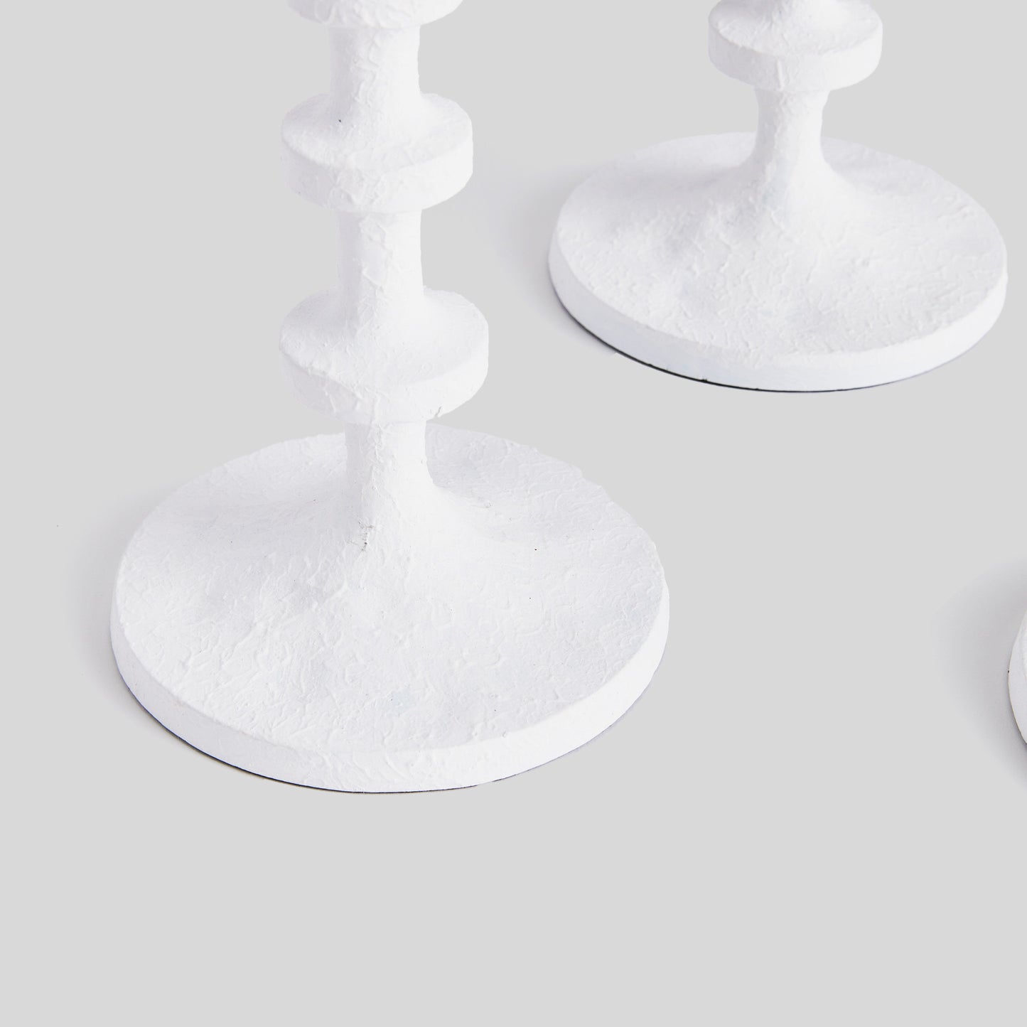 Closeup view of minimalist taper candleholders in white.