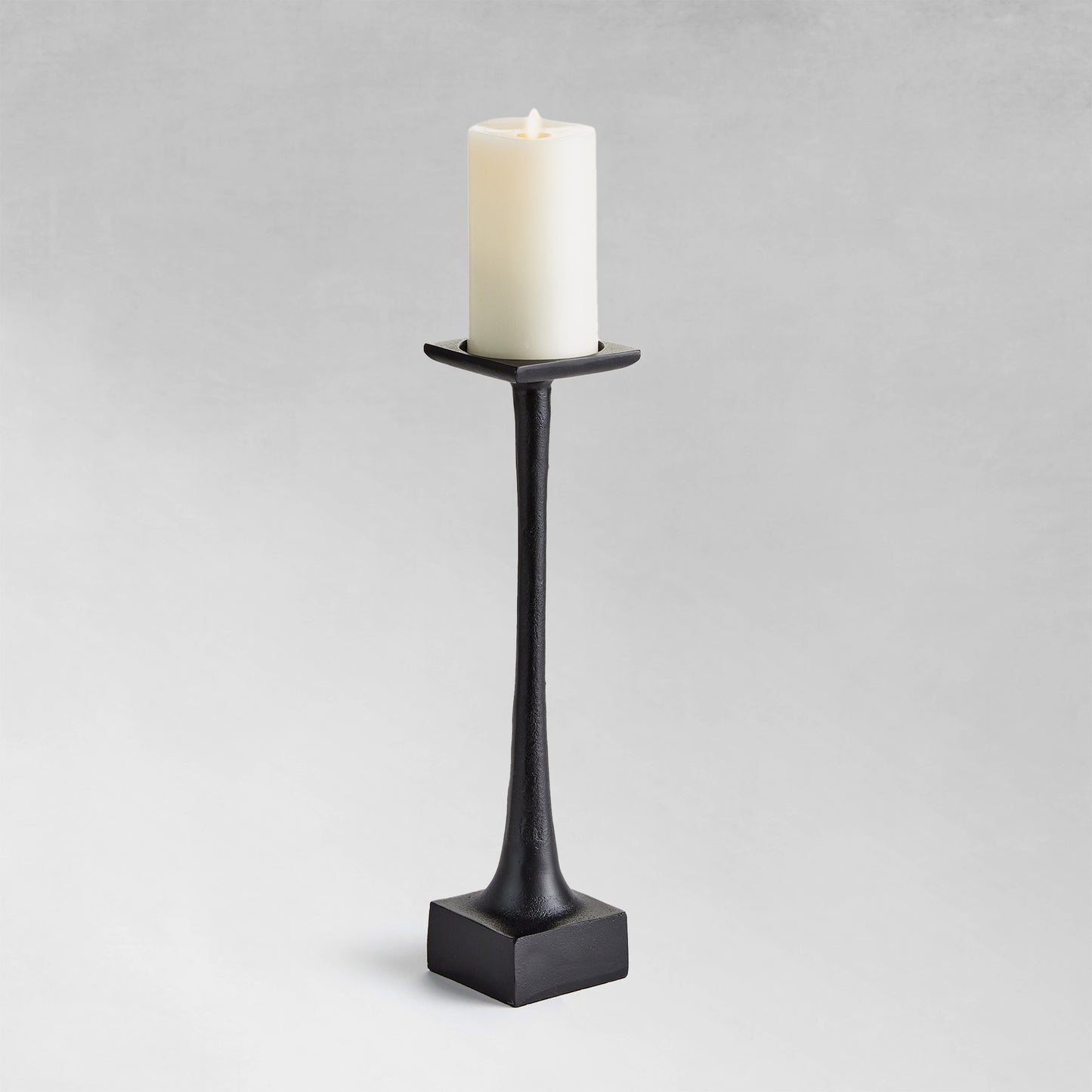 Medium modern pillar candleholder with black finish and gray background.