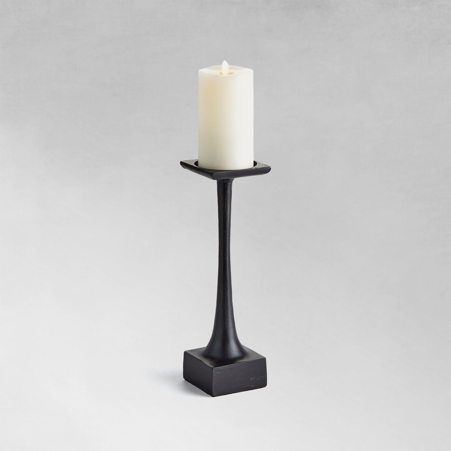 Small modern pillar candleholder with black finish and gray background.