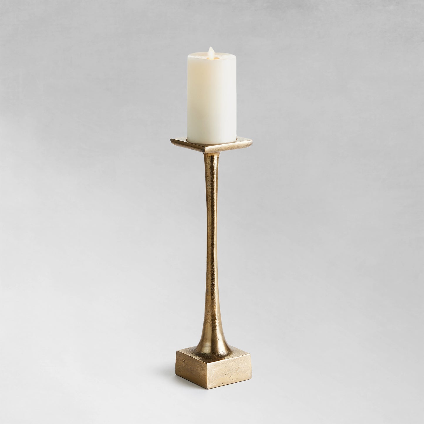 Medium modern pillar candleholder with champagne finish and gray background.
