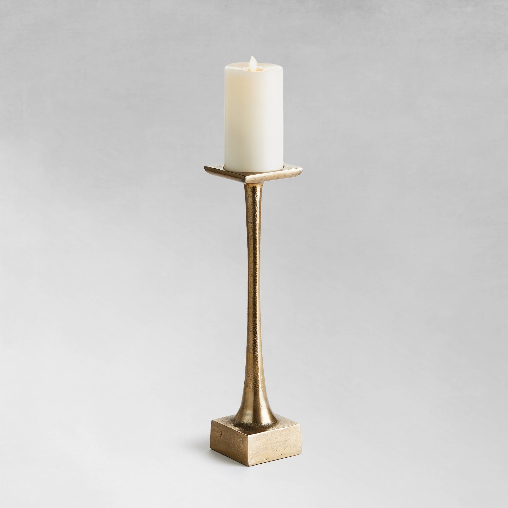 Medium modern pillar candleholder with champagne finish and gray background.