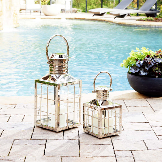 Nautical polished metal outdoor lanterns stylized next to pool with blue water.