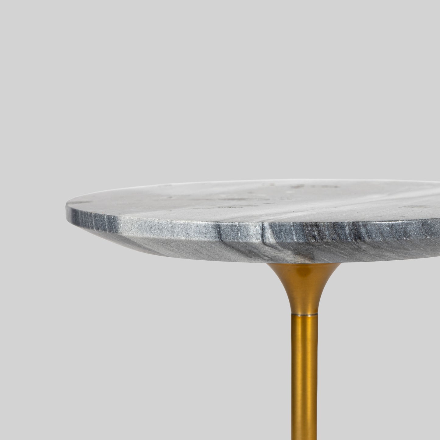 Small round cocktail table with marble top and brass base on a light gray background.