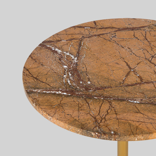 Small round cocktail table with marble top and brass base on a light gray background.