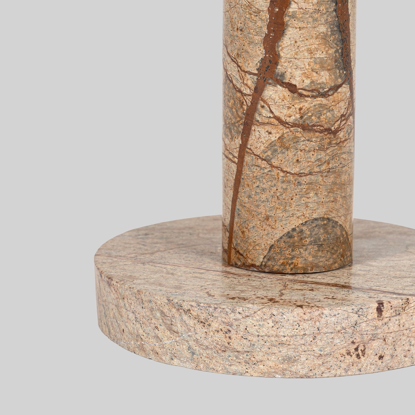 Small round cocktail table with marble top and brass base on a light gray background.